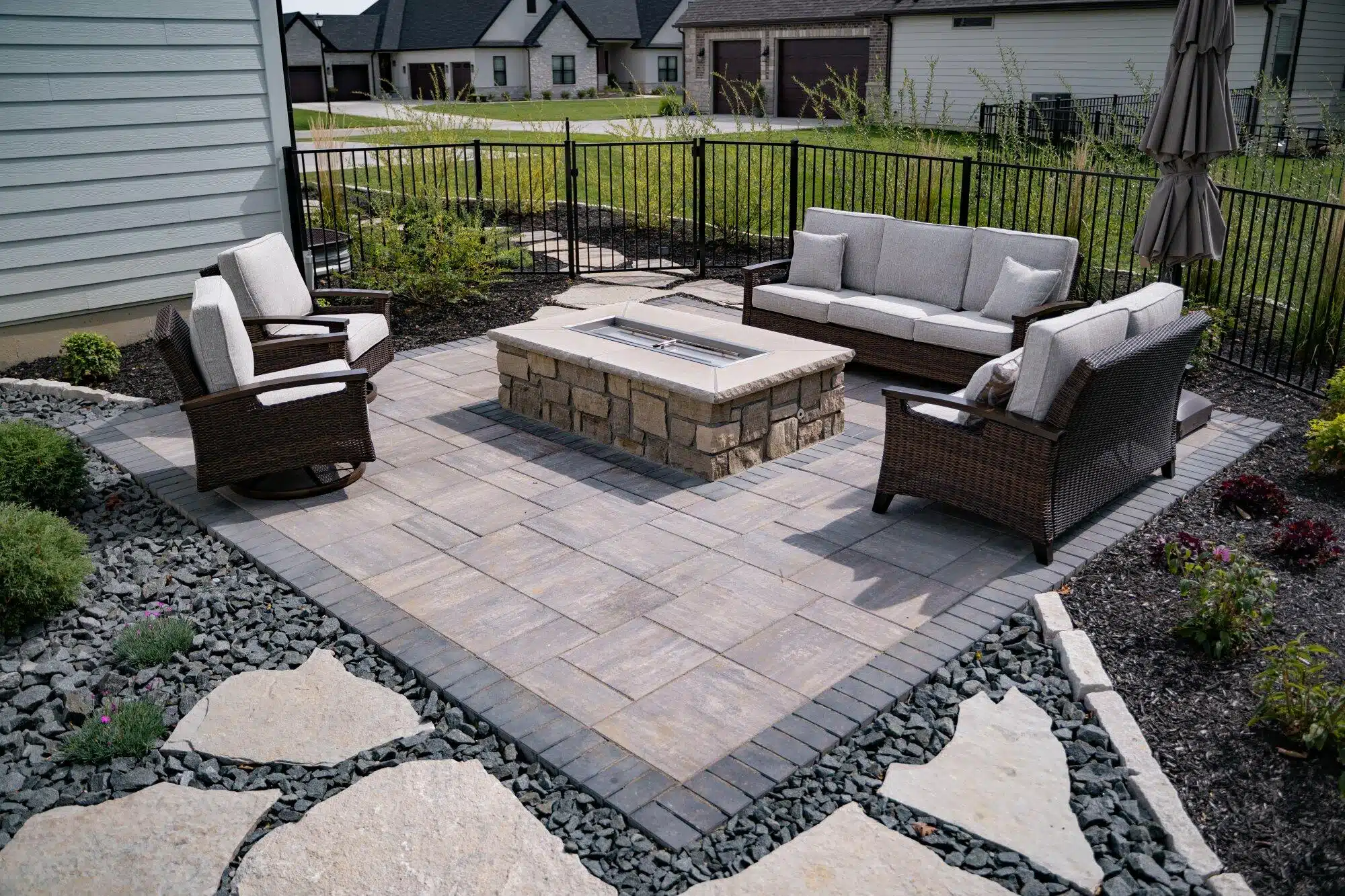 A finished paver patio with a stone fire pit and outdoor seating
